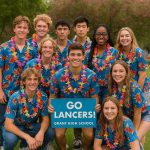 Fun group photo of highschoolers in bright Hawaiian shirts outside